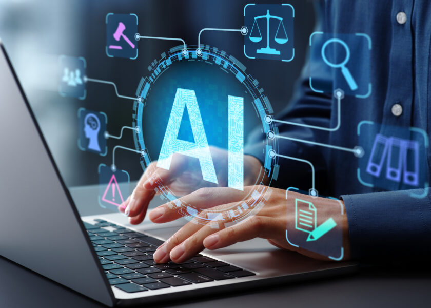 Businessman typing on laptop computer keyboard at desk in office.